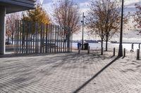 an empty brick pathway in front of a building with benches on the pavement near by