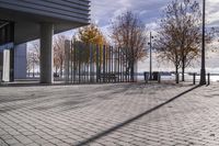 an empty brick pathway in front of a building with benches on the pavement near by