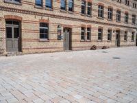 an empty brick sidewalk outside a large building that is near a clock tower in front