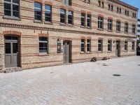 an empty brick sidewalk outside a large building that is near a clock tower in front