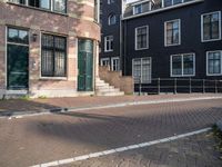 an empty brick street lined with buildings and a person skateboarding with their board in front of them