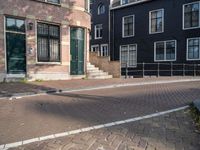 an empty brick street lined with buildings and a person skateboarding with their board in front of them