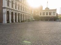 a man is standing in an empty brick street at sunrise time, taking a picture