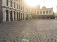 a man is standing in an empty brick street at sunrise time, taking a picture