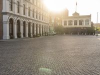 a man is standing in an empty brick street at sunrise time, taking a picture