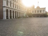 a man is standing in an empty brick street at sunrise time, taking a picture