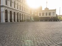 a man is standing in an empty brick street at sunrise time, taking a picture