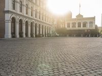 a man is standing in an empty brick street at sunrise time, taking a picture