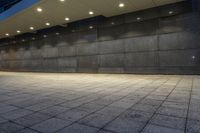 an empty brick walkway at night lite by several light bulbs and concrete blocks,