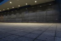 an empty brick walkway at night lite by several light bulbs and concrete blocks,