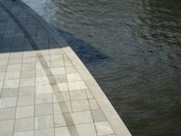 an empty brick walkway with water surrounding it on a sunny day in the summertime