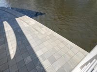 an empty brick walkway with water surrounding it on a sunny day in the summertime