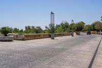 empty bricked sidewalk with palm trees and benches in it under a blue sky at an outdoor park