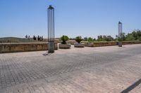 empty bricked sidewalk with palm trees and benches in it under a blue sky at an outdoor park