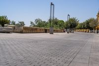 empty bricked sidewalk with palm trees and benches in it under a blue sky at an outdoor park