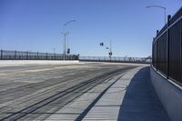 an empty bridge with no cars on it and a black fence to keep drivers away from the sun