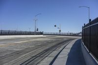 an empty bridge with no cars on it and a black fence to keep drivers away from the sun