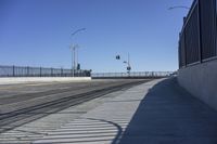 an empty bridge with no cars on it and a black fence to keep drivers away from the sun