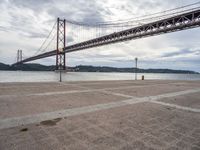 an area near the water and a bridge over it is empty and empty and there are no cars on it