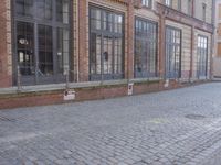 an empty building is shown with some signs on the sidewalk and a street light near by