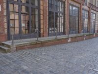 an empty building is shown with some signs on the sidewalk and a street light near by