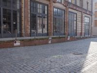 an empty building is shown with some signs on the sidewalk and a street light near by