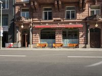 a building with a couple of benches in front of it that is empty on a city street