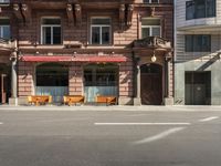 a building with a couple of benches in front of it that is empty on a city street