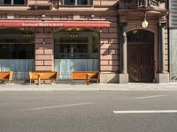 a building with a couple of benches in front of it that is empty on a city street