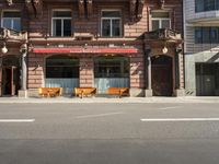 a building with a couple of benches in front of it that is empty on a city street