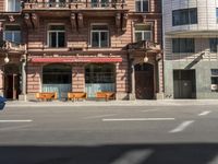 a building with a couple of benches in front of it that is empty on a city street