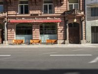 a building with a couple of benches in front of it that is empty on a city street