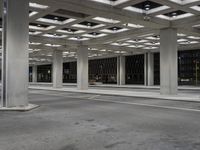 an empty building with two floors in front of a parking lot with columns and lights on