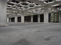 an empty building with two floors in front of a parking lot with columns and lights on