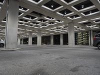 an empty building with two floors in front of a parking lot with columns and lights on