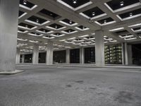 an empty building with two floors in front of a parking lot with columns and lights on