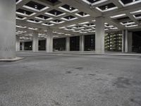 an empty building with two floors in front of a parking lot with columns and lights on