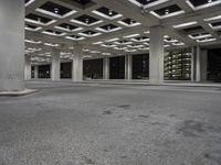 an empty building with two floors in front of a parking lot with columns and lights on