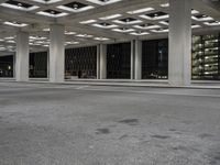 an empty building with two floors in front of a parking lot with columns and lights on