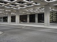 an empty building with two floors in front of a parking lot with columns and lights on