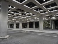 an empty building with two floors in front of a parking lot with columns and lights on