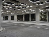 an empty building with two floors in front of a parking lot with columns and lights on