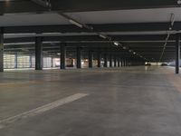 a large, empty building with two cars parked in it's carping area