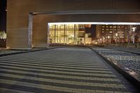 a paved walkway leads through an empty building, with windows and brick walls and cobblestone floors