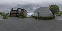 a fish eye lens view of an empty building and driveway with shrubs, bushes and shrubs on it