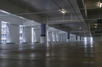 an empty building with concrete floors and large windows and some metal beams with sign in center