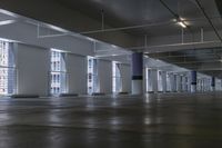 an empty building with concrete floors and large windows and some metal beams with sign in center
