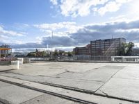 empty building lot with old rail tracks running across the concrete ground and blue sky with white clouds