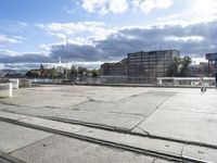 empty building lot with old rail tracks running across the concrete ground and blue sky with white clouds