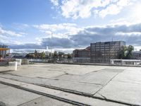 empty building lot with old rail tracks running across the concrete ground and blue sky with white clouds